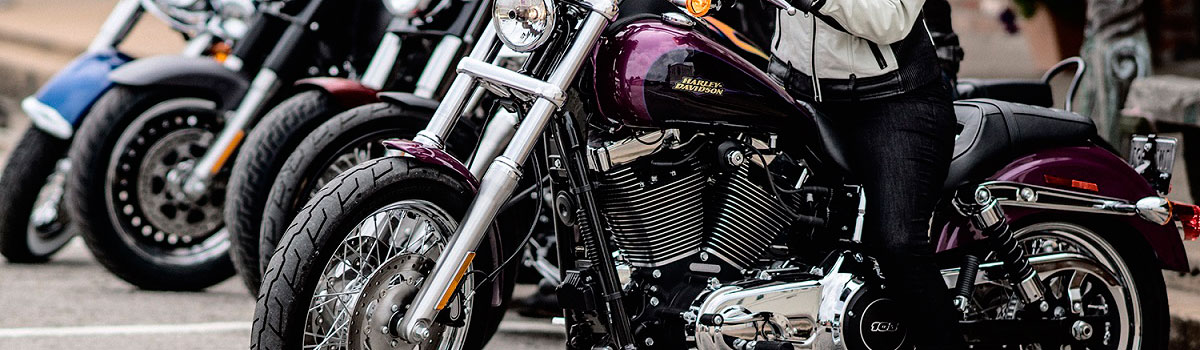 Close-up image of a maroon and black Harley-Davidosn® motorcycle with other bikes in the background.